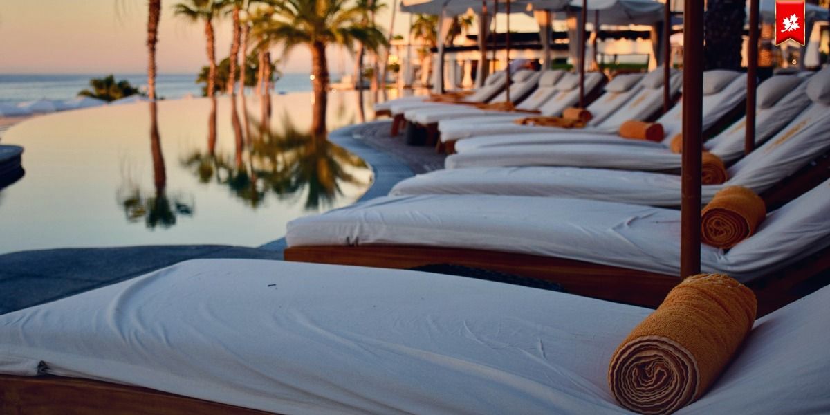 White sun loungers beside an infinity pool with palm trees – airport transfer to Marquis