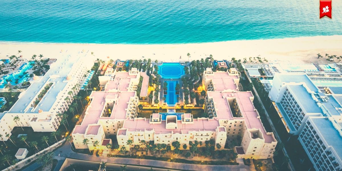 Aerial view of a beachfront resort with a long central pool – airport transfer to Riu Palace
