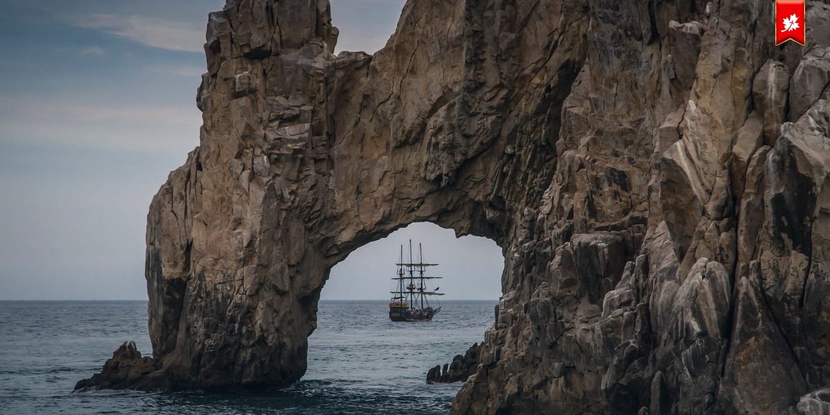 Land's End arch framing a tall ship on the sea – airport transfer to Sandos Finisterra